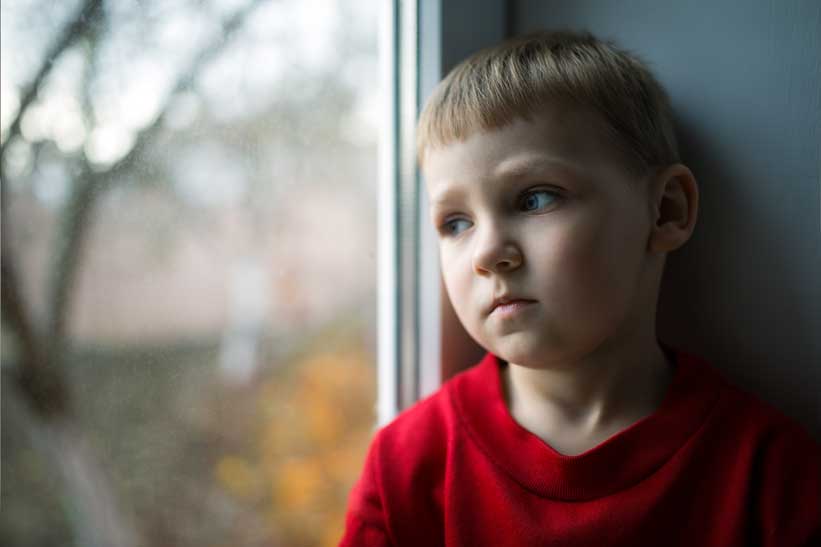 little girl looks out the window, sad.